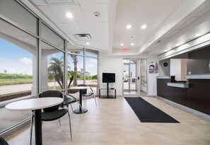 A modern reception area with a TV, a reception desk, and a seating area with chairs and a table. - 3 Pet-Friendly Ingleside Rooms w/ Kitchen, Free Parking | Onsite Pool Access (Ingleside)