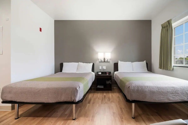 A hotel room with two beds, a nightstand, a lamp, and a window with curtains. - 4 Budget-Friendly Rooms for Ingleside Stay! Kitchen, Free Parking, Onsite Pool (Ingleside)