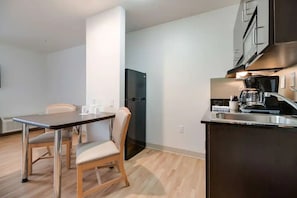 A compact kitchen with a dining area, a black refrigerator, stainless steel appliances, and a wooden dining table. - 4 Budget-Friendly Rooms for Ingleside Stay! Kitchen, Free Parking, Onsite Pool (Ingleside)