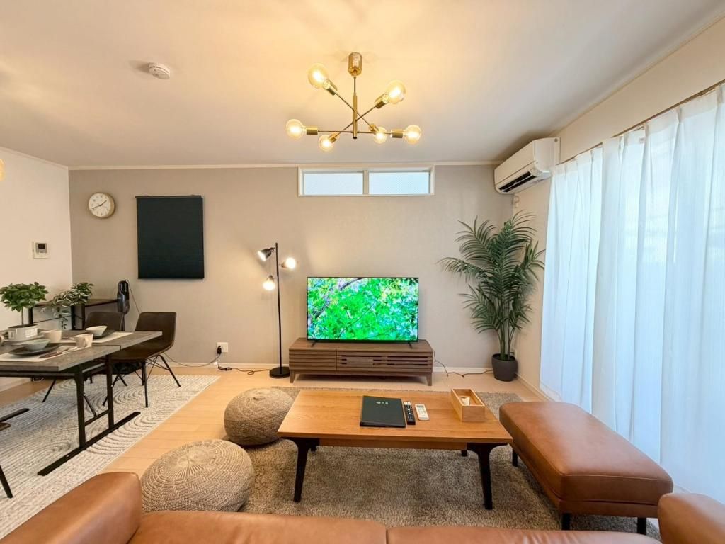 A modern living room with a flat-screen TV, a coffee table, a sofa, and a dining area with a table and chairs.