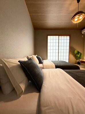 A room with two beds, a large window, and a hanging light fixture. - Miki Moon&Bird Bentencho Private Villa (Osaka)