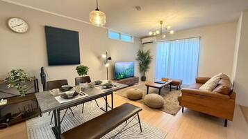 A modern living room with a dining area, a sofa, and a television.