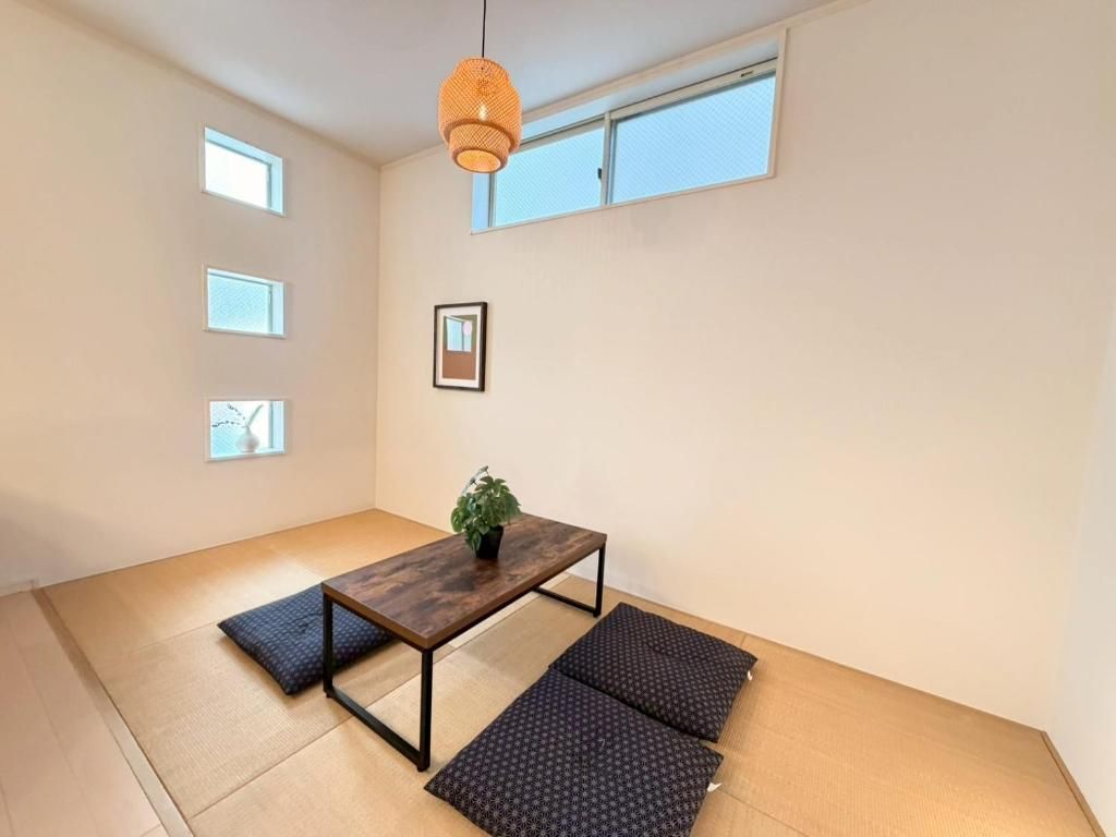 A minimalist room with tatami flooring, a low wooden table with a plant, and a hanging light fixture.