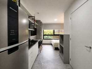 Eine kompakte Küche mit integriertem Kühlschrank, Mikrowelle und einer kleinen Essecke.