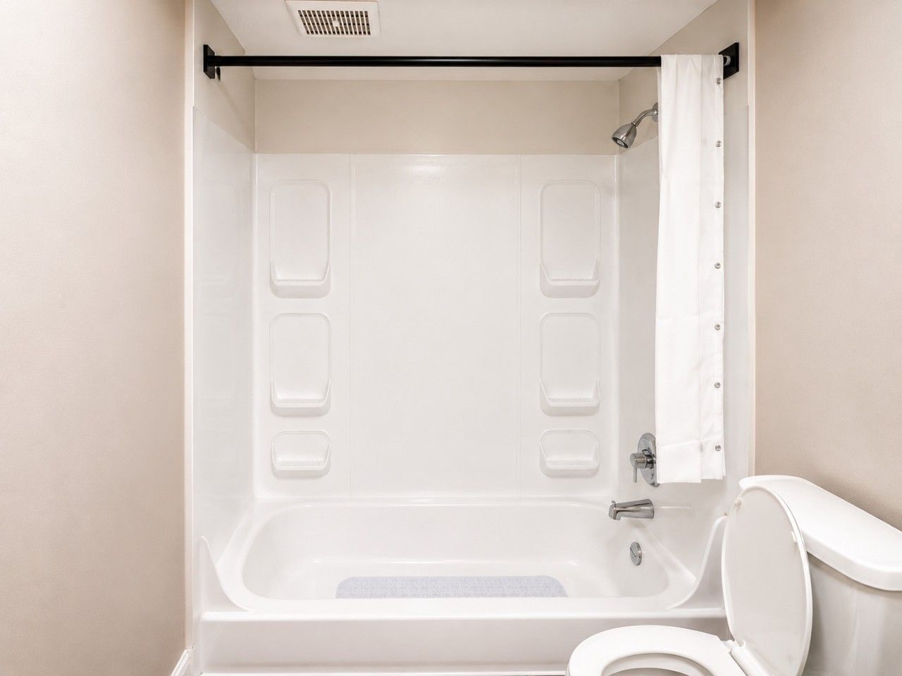 A bathroom with a bathtub, a toilet, and a shower curtain.