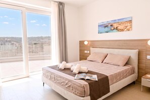 A modern bedroom with a large bed, a view of the city through a balcony, and a painting on the wall. - Penthouse, Jacuzzi & Sea-view In Gozo 7b, Marsalforn Iz-Zebbug Gozo, Malta (Marsalforn Iz-Zebbug Gozo)