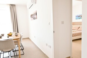A modern, minimalistic room with a dining area, a bed, and a view of the sea. - Penthouse, Jacuzzi & Sea-view In Gozo 7b, Marsalforn Iz-Zebbug Gozo, Malta (Marsalforn Iz-Zebbug Gozo)
