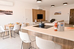 Eine moderne Küche mit Kochinsel, Essbereich und Fernseher an einer Wand aus Holzpaneelen.
