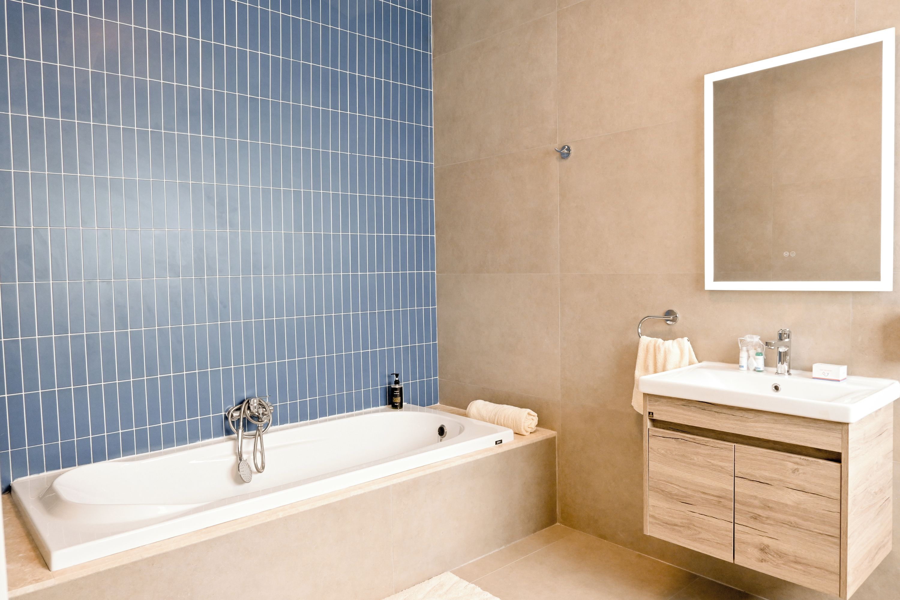 Een moderne badkamer met een groot bad, een wastafel met spiegel en een betegelde wand.