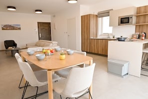 A modern kitchen with a microwave, toaster, and sink. There is a dining table with chairs and a fruit bowl. - Penthouse, Jacuzzi & Sea-view In Gozo 7b, Marsalforn Iz-Zebbug Gozo, Malta (Marsalforn Iz-Zebbug Gozo)