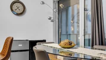 A modern kitchen with a dining table, chairs, a clock, and a window with curtains.