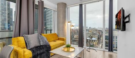Uma sala de estar moderna com um sofá amarelo, uma mesa de centro e uma janela grande com vista para a cidade.