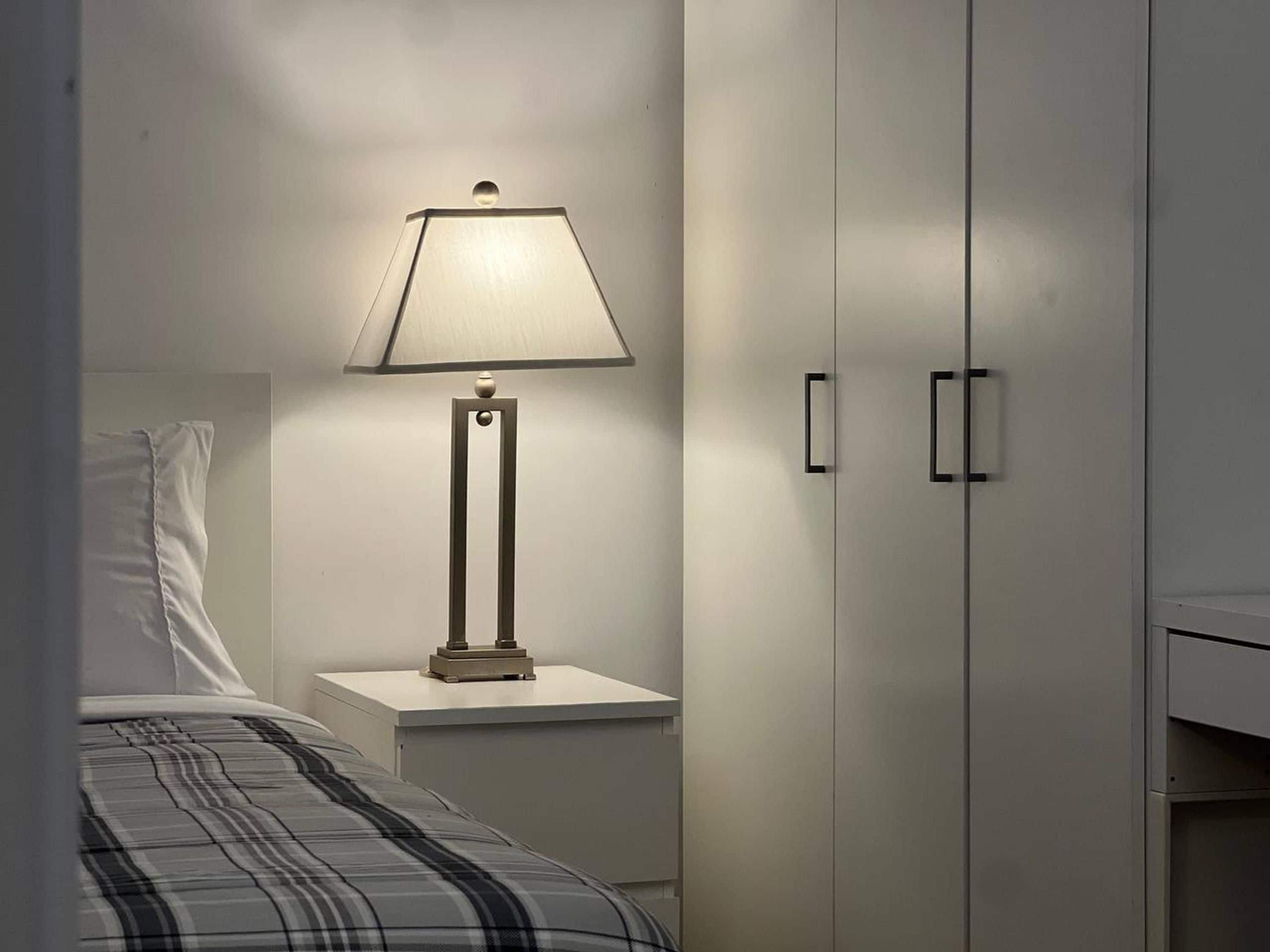 Ein Schlafzimmer mit einem Bett, einem Nachttisch mit Lampe und einem Kleiderschrank.