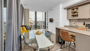 A modern apartment with a dining area, kitchen, and large windows offering a city view. - StayToronto - The Entertainment Suites (Toronto)