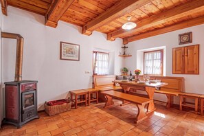 Ein gemütlicher Essbereich mit Holzmöbeln, einem Kamin und einer im Hintergrund sichtbaren Küche.