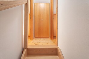 A narrow wooden staircase leading to a room with a wooden wardrobe.