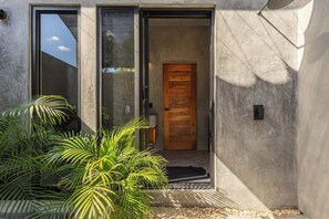 Fachada moderna de un edificio con puerta corredera de vidrio, puerta de madera y exterior de concreto.