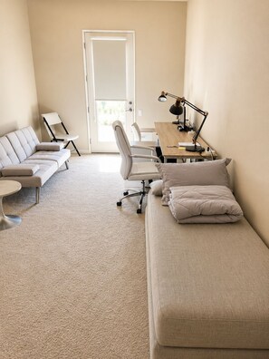 A modern, minimalist room with a sofa, a desk, and a chair. - Palm Desert 4-Bedroom Retreat with a sparkling pool in the heart of Palm Desert (Palm Desert)