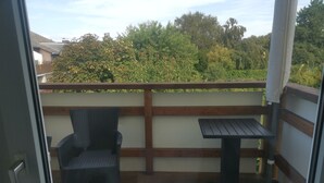 Un balcone con pavimento in legno, una sedia e un tavolino.