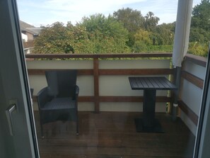 A balcony with a wooden floor, a chair, and a small table. - Eulenhaus - FeWo OG (Cuxhaven)
