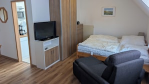 Una camera da letto con un letto, una TV su un mobile, un armadio e un tavolino.