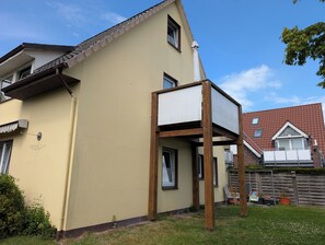 Ein zweistöckiges Haus mit einem Fenster, einer Tür und einem kleinen Garten.