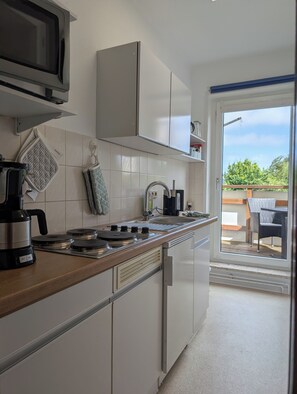 Eine moderne Küche mit Gasherd, Kaffeemaschine und Blick auf eine Terrasse.