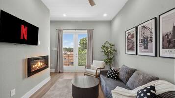 Bright modern lounge with fireplace, TV, and balcony access