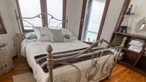 A bedroom with a bed, wooden floor, and a window. - Brewer’s Bluff | Iconic Ocean View Estate (Lincoln City)