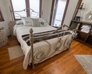 Un dormitorio con cama, suelo de madera y una ventana.