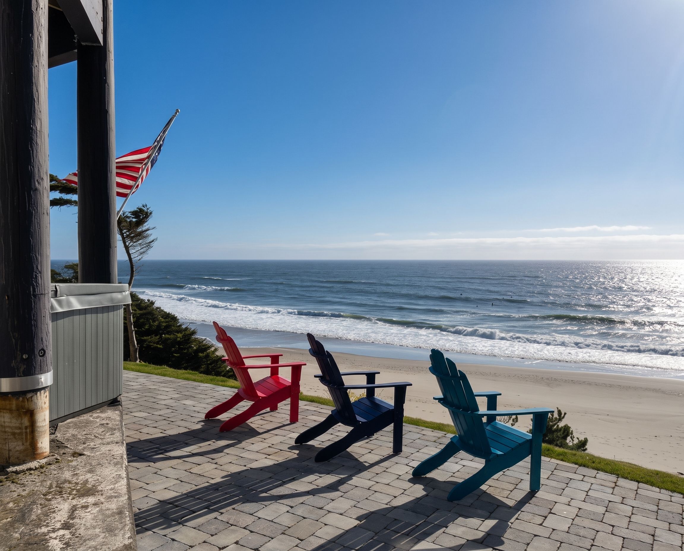Uitzicht op het strand met een rij Adirondack-stoelen gericht op de oceaan, een vlaggenmast met de Amerikaanse vlag, en een gebouw-ingang.
