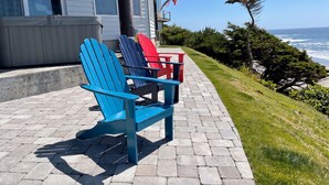 A coastal property with a patio featuring Adirondack chairs, an American flag, and a view of the ocean. - Brewer’s Bluff | Iconic Ocean View Estate (Lincoln City)