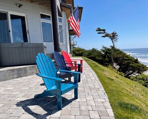 Una propiedad costera con un patio que incluye sillas Adirondack, una bandera estadounidense y vistas al océano.