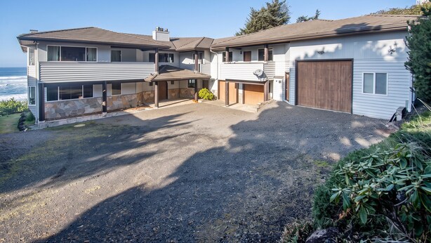 A two-story house with a garage, a covered patio, and a view of the ocean. - Brewer’s Bluff | Iconic Ocean View Estate (Lincoln City)