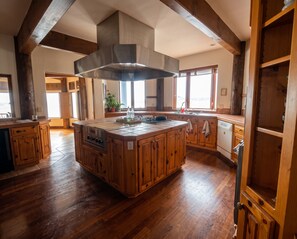 Una cocina amplia con una isla grande, muebles de madera y una campana extractora de acero inoxidable.