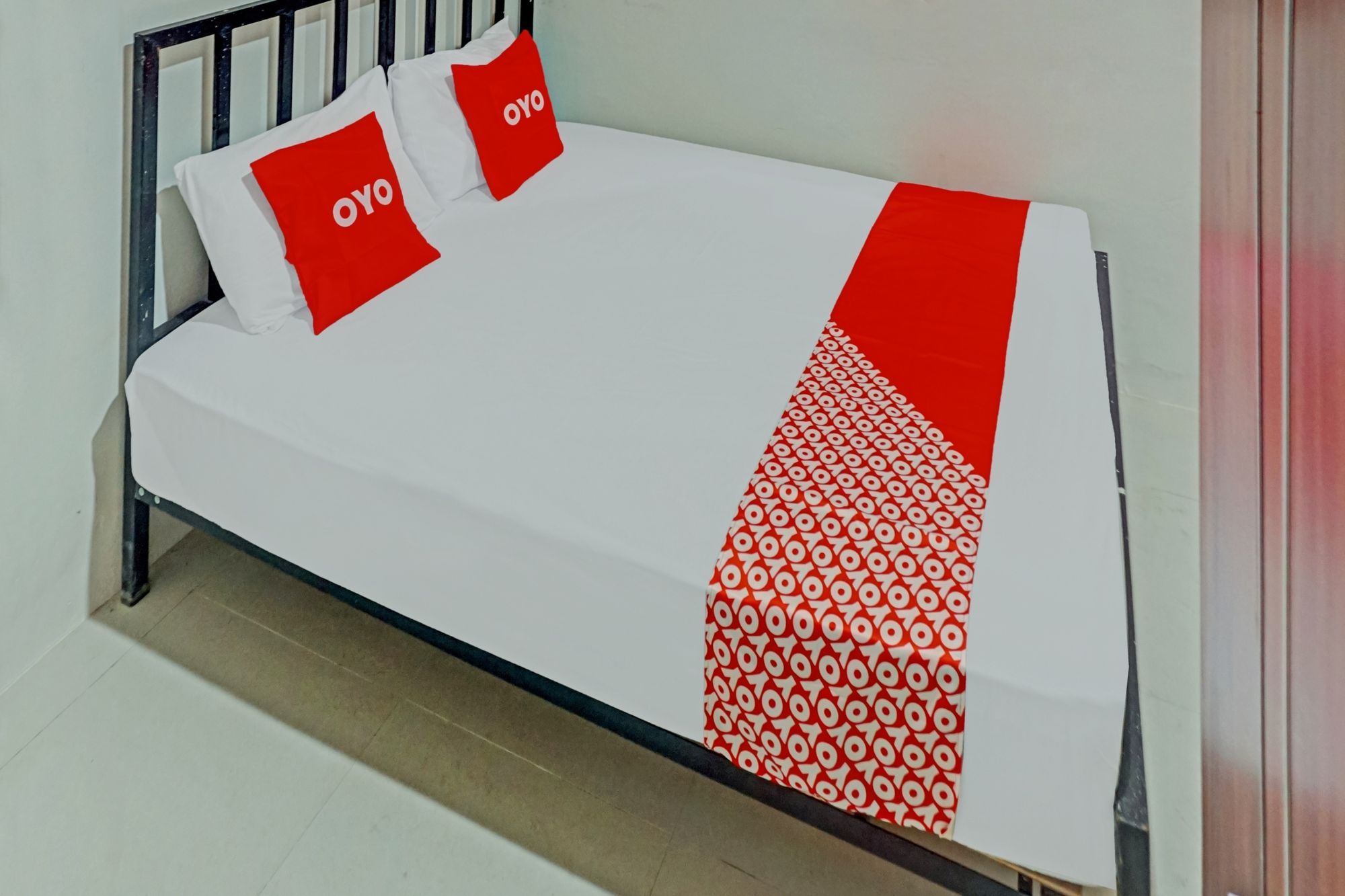 Una cama con colchón blanco y dos almohadas con texto rojo.