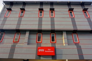Ein Gebäude mit grauer Fassade und roten Akzenten, ausgestattet mit zahlreichen Fenstern und einem Schild für 'OYO Guesthouse'.