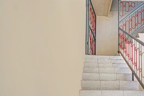 Un escalier avec des marches blanches et des rampes en métal rouge.