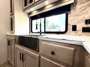 A kitchen with a window, stainless steel sink, and marble backsplash. - Luxury glamping suite near beaches & OWA, POOL! (Foley)