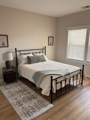 Une chambre à coucher avec un lit, une table de chevet, une lampe et un tapis à motifs.