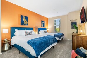 A hotel room with two beds, a large window, and a flat-screen TV.
