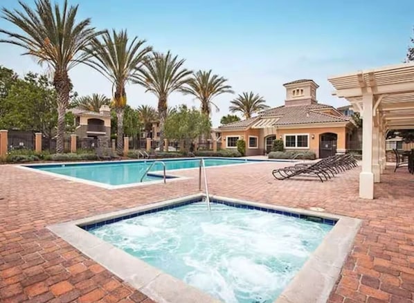 Un espace bien-être comprenant un jacuzzi, une piscine et des chaises longues.