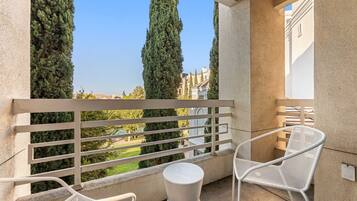 A balcony with a white metal railing, two white wicker chairs, and a small round table.