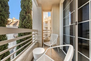 A balcony with a white railing, two white chairs, and a small table.