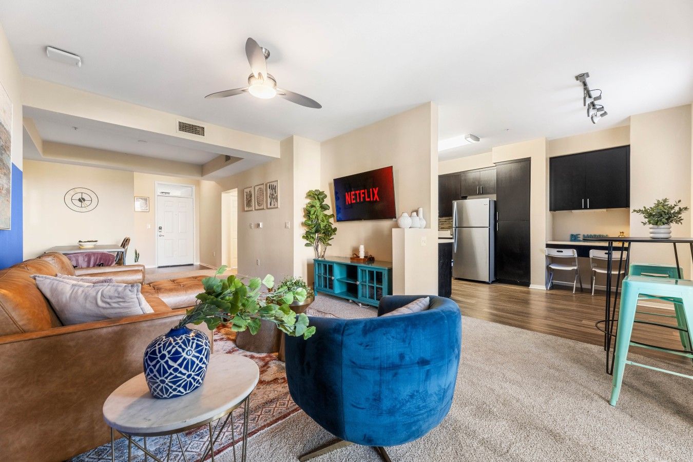 A modern living room with a sofa, a blue armchair, and a coffee table with decorative items.