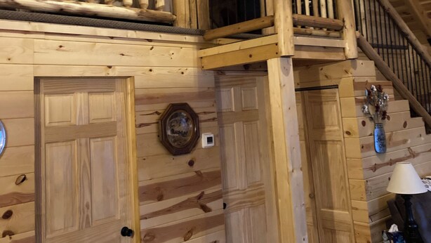 A wooden interior with a staircase, wooden doors, and a wall-mounted light fixture. - Cozy 2-bedroom cabin in adorable Tomahawk with AC (Tomahawk)