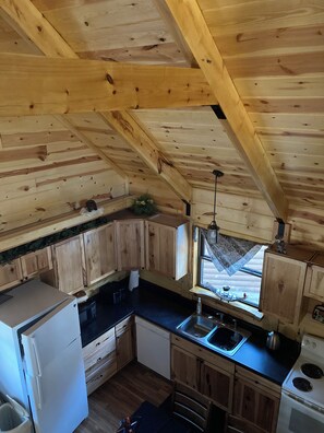 A compact kitchen with wooden cabinets, a refrigerator, a sink, and a stove. - Cozy 2-bedroom cabin in adorable Tomahawk with AC (Tomahawk)