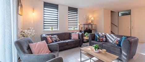 A modern living room with two sofas, a coffee table, and a bookshelf.