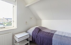 A bedroom with a single bed, a small white bedside table, a window, and a radiator. - Lovely home in Wemeldinge with sauna (Wemeldinge)
