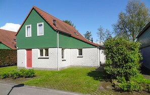 A two-story house with a green facade and a red door, surrounded by a well-maintained lawn and a small garden. - Lovely home in Wemeldinge with sauna (Wemeldinge)